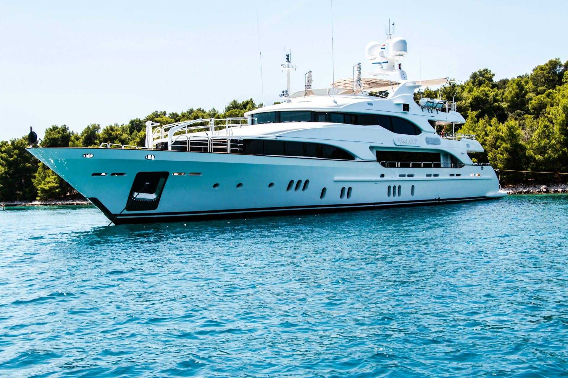 Yacht at anchor along a wooded coastline